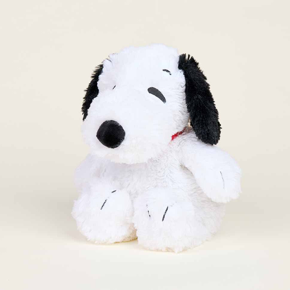 Plush toy resembling a black and white dog with a red collar on a beige background