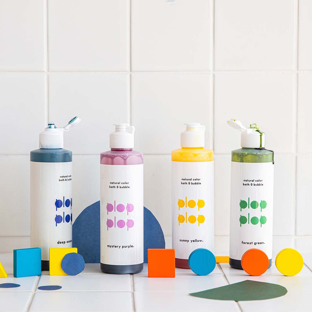Four bottles of Pop by Nature on a tiled floor with colorful caps and labels.