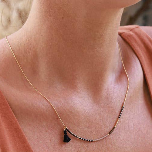 Woman wearing a necklace with a subtle smile, blurred background