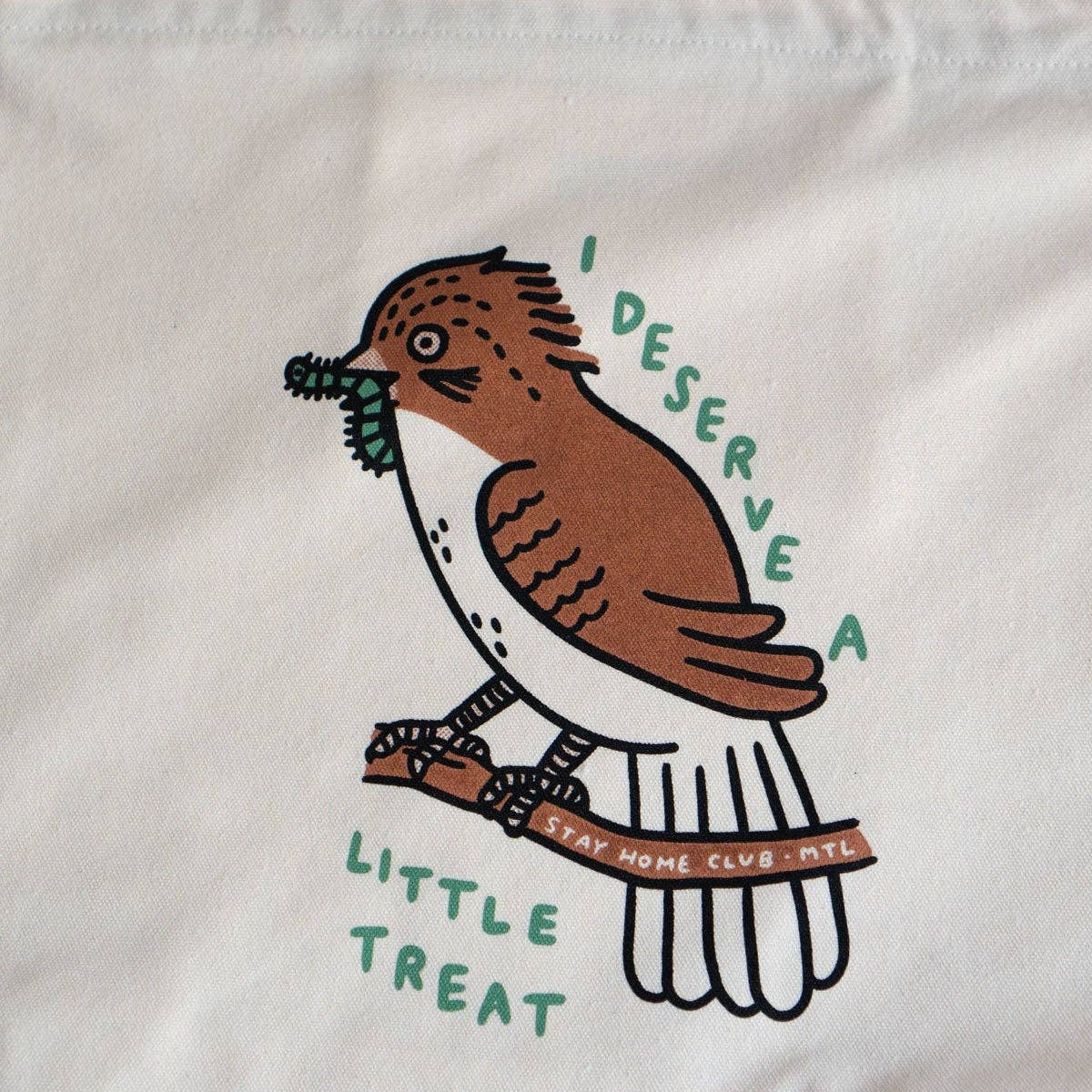 Tote bag with a bird illustration and text on a marble surface