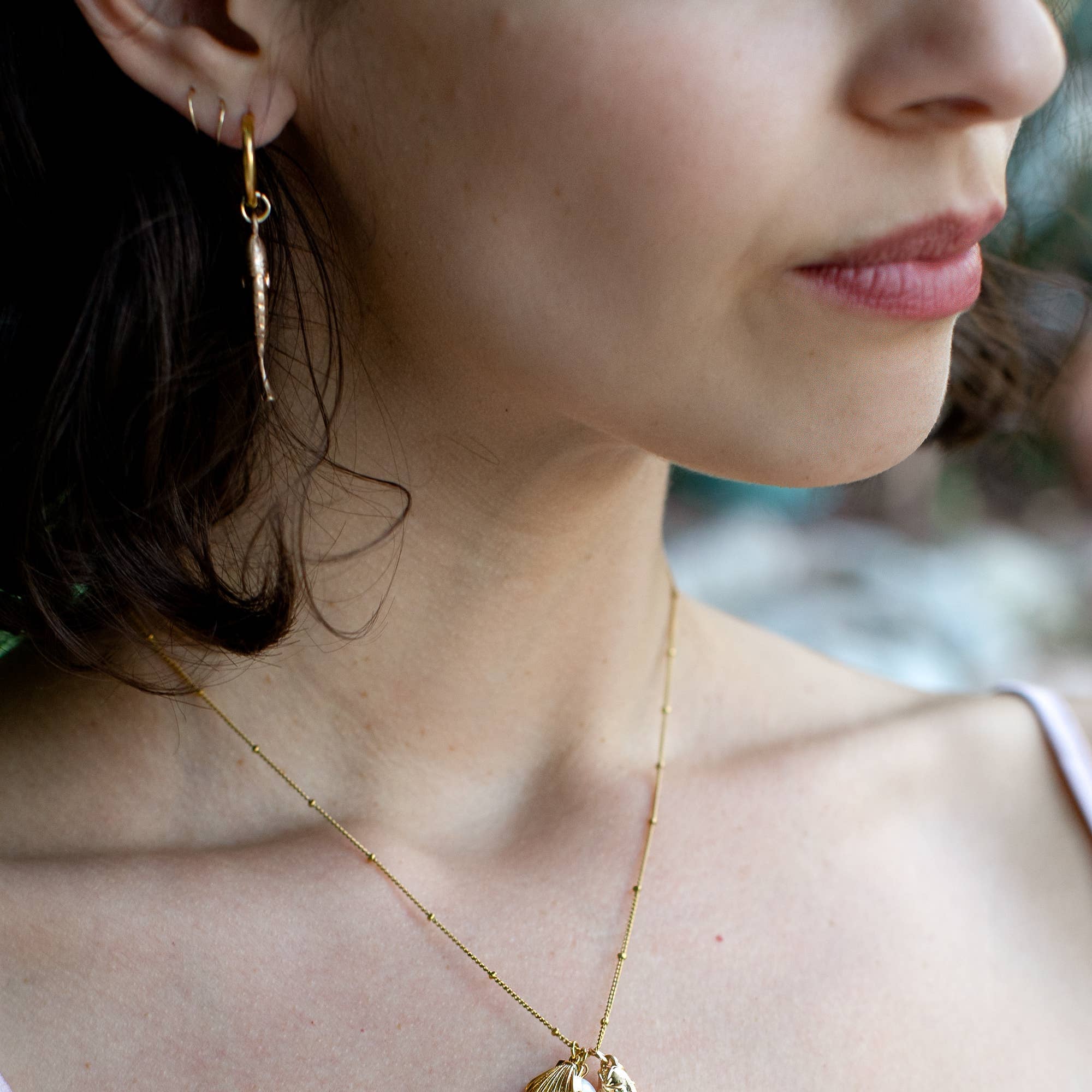 Close-up of a person wearing a gold necklace with a unique pendant.