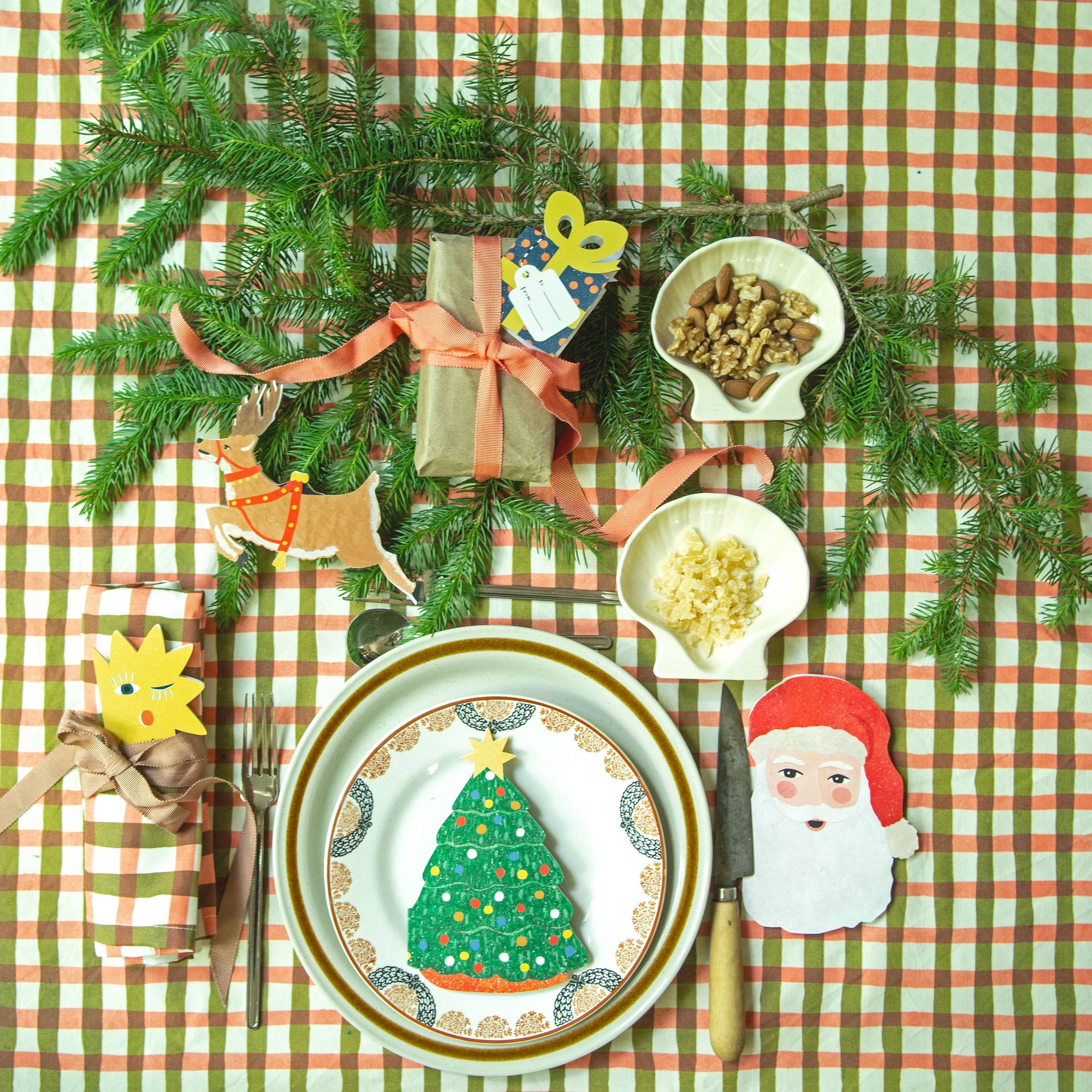 Christmas-themed table setting with decorations on a checkered tablecloth