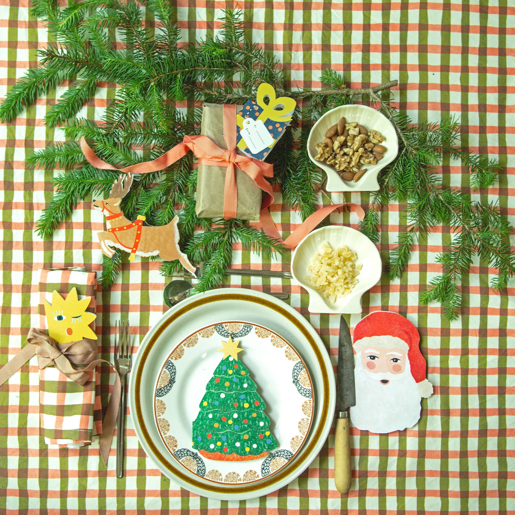 Christmas-themed table setting with decorations on a checkered tablecloth