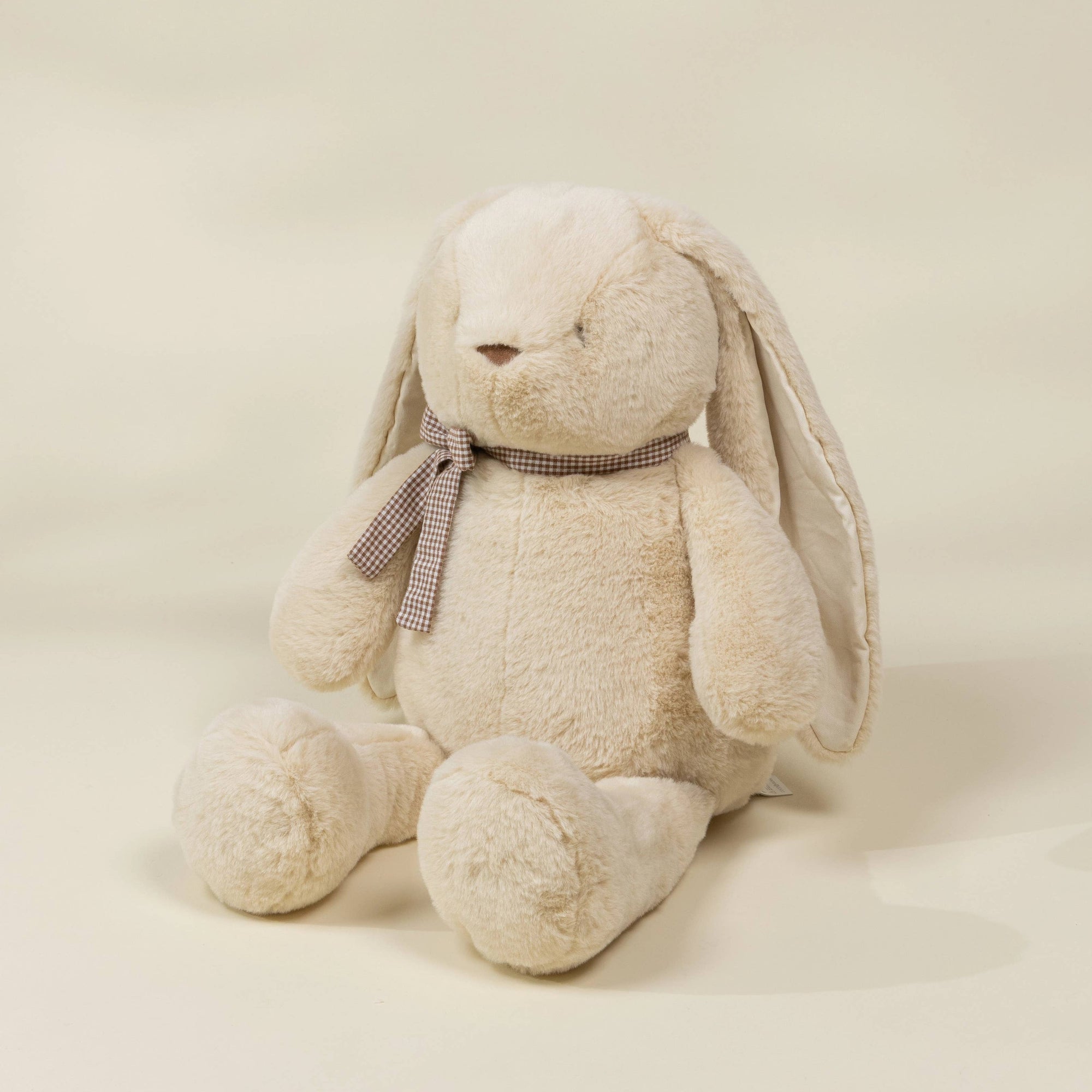 Beige stuffed bunny with a bow tie on a beige background