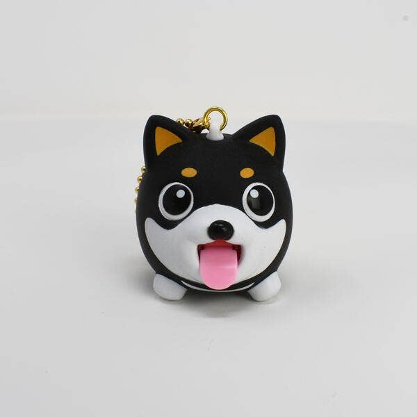 Black and white dog-shaped keychain with a pink tongue on a light gray background