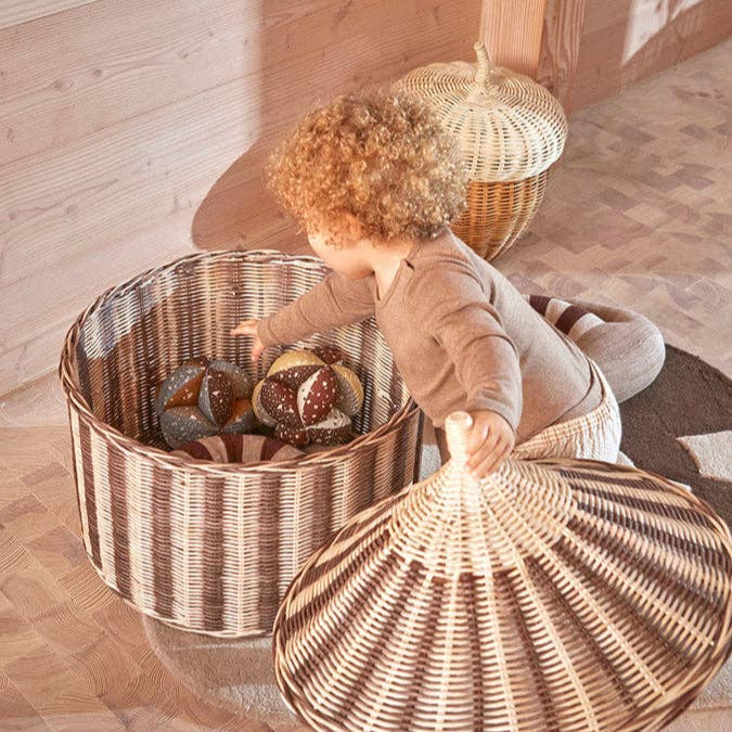 Child playing with wicker baskets on a wooden floor