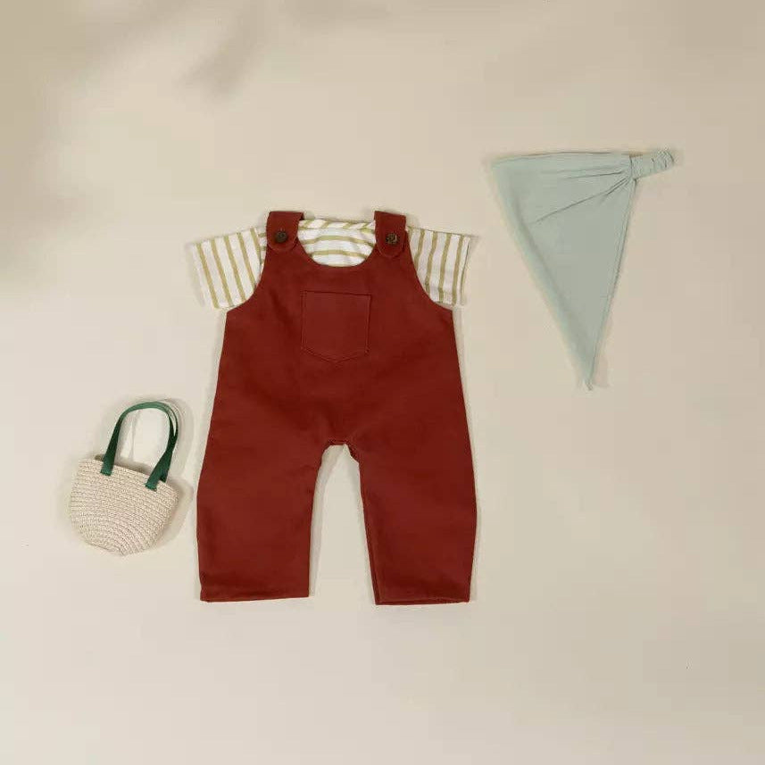 Red overalls with a striped shirt, small bag, and headband on a beige background