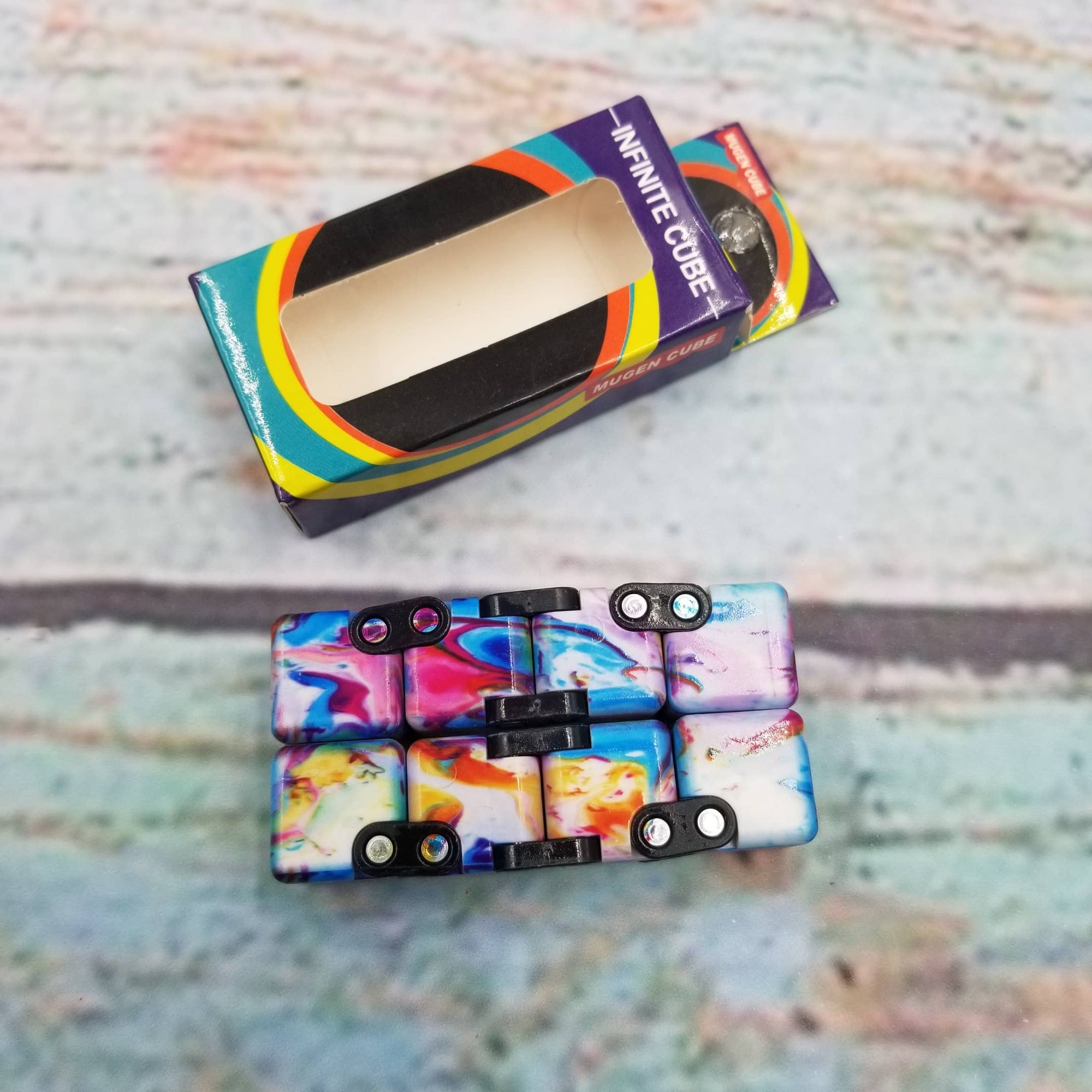 Colorful phone case with 'Infinite Cube' packaging on a textured surface