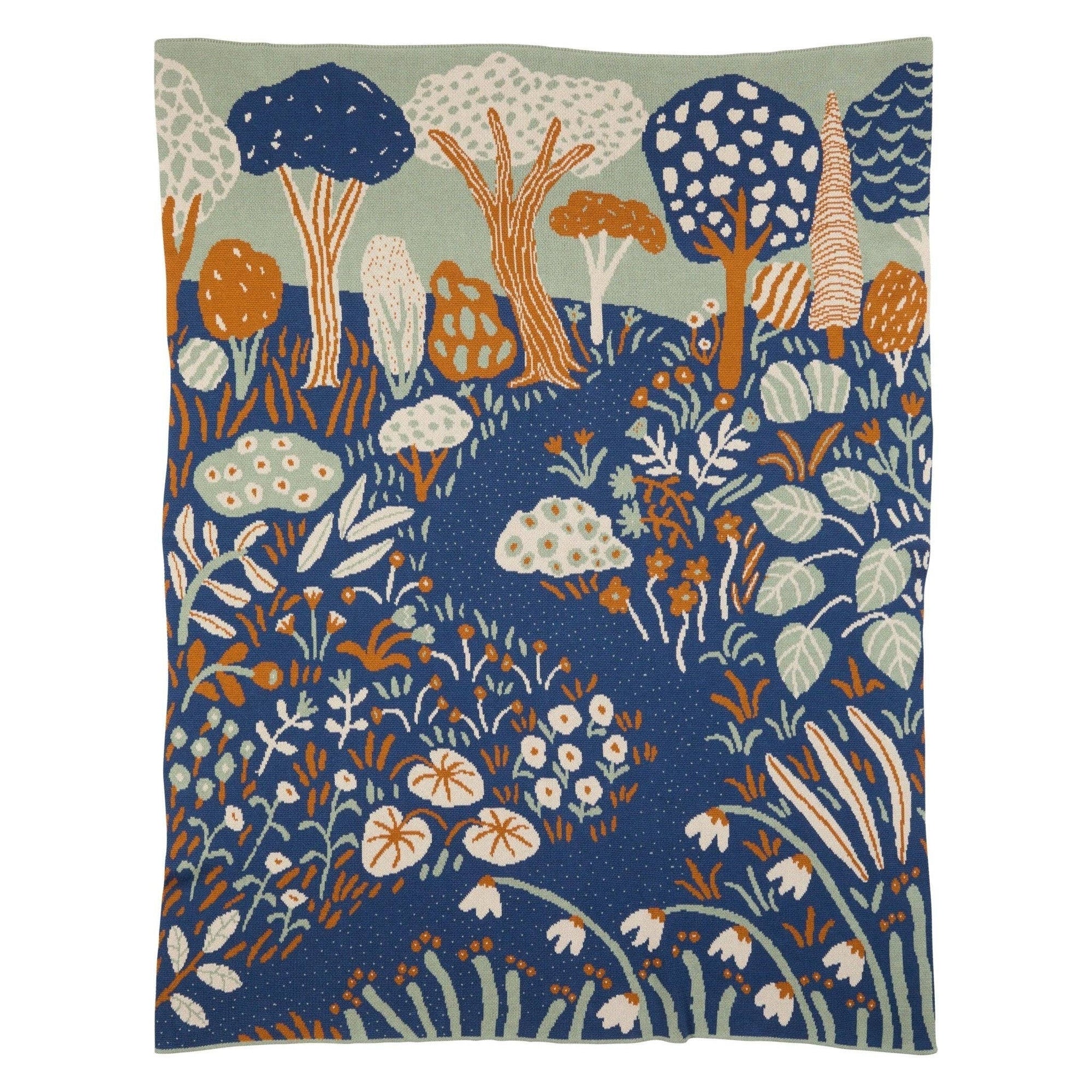 Decorative blanket with a forest design featuring trees, flowers, and plants on a blue background.