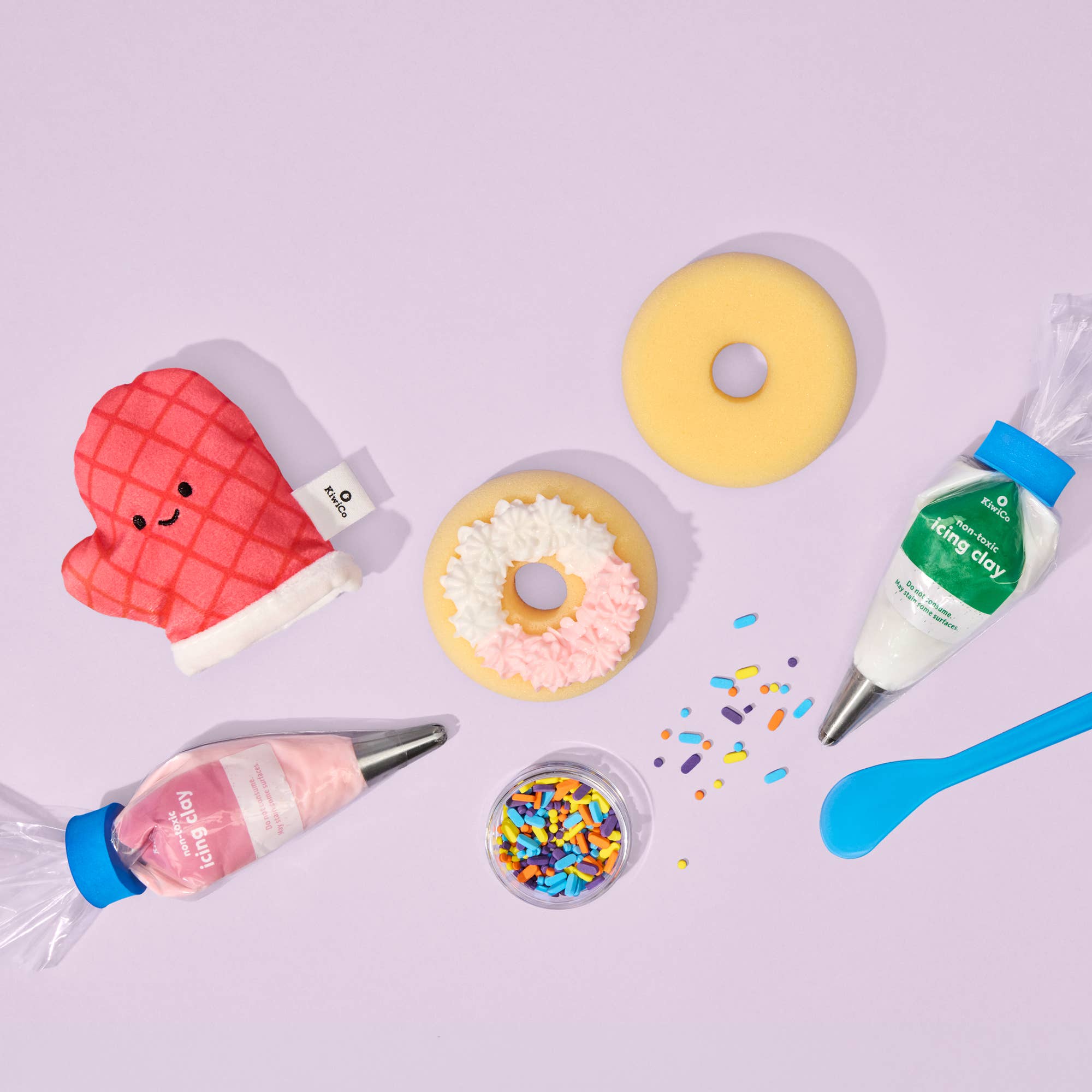 Decorative icing bottles, donuts, and sprinkles on a light purple background