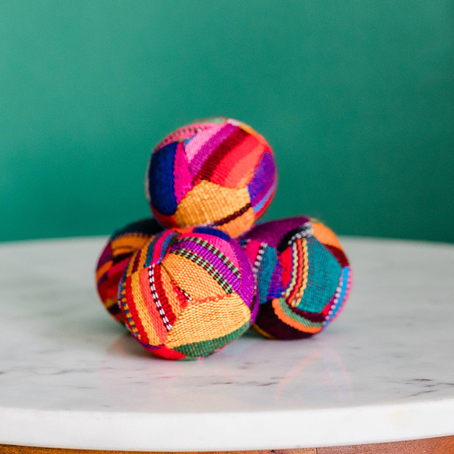 Colorful woven balls on a marble surface with a green background