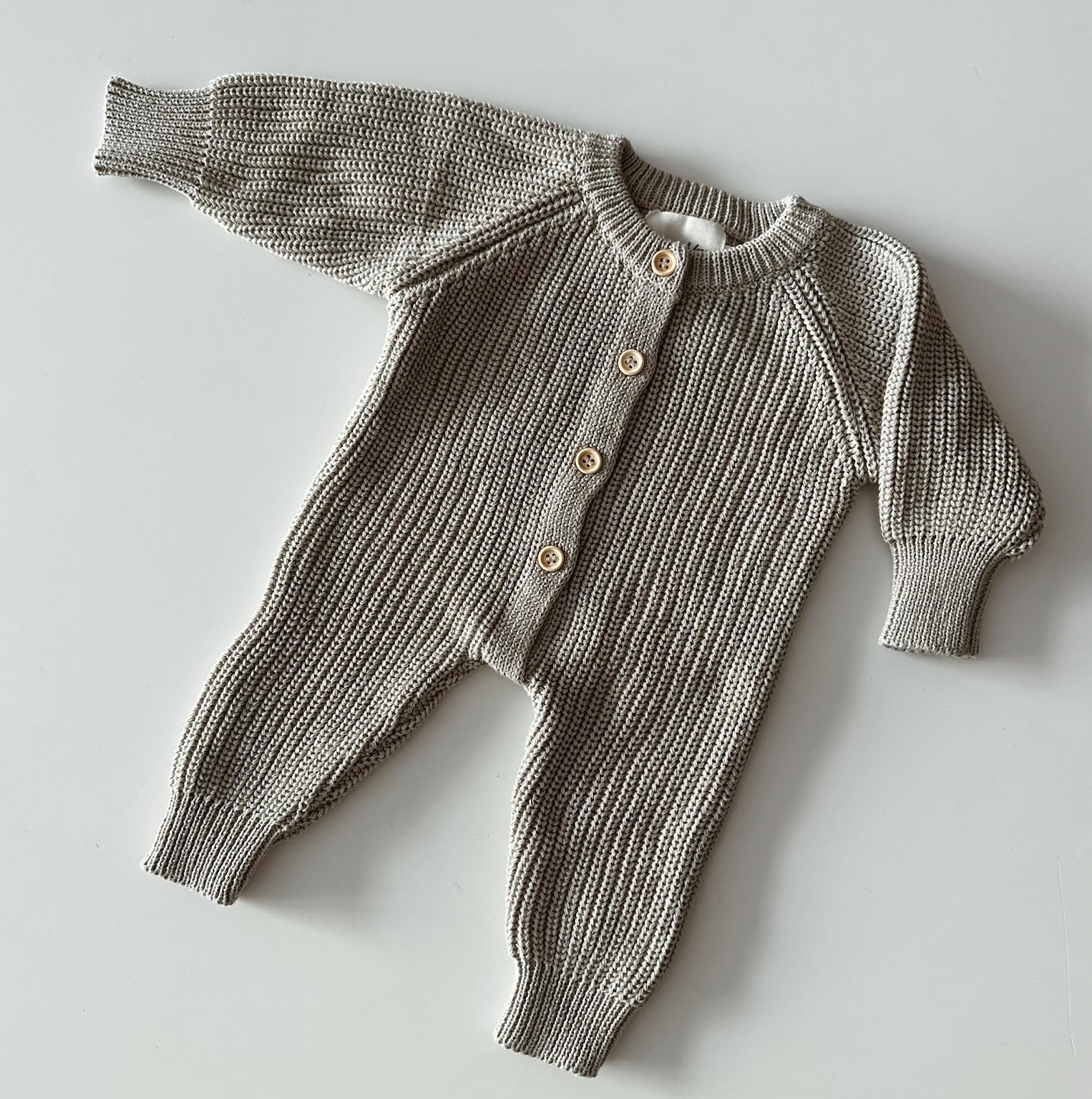 Knitted baby outfit with a cardigan and pants on a light gray background