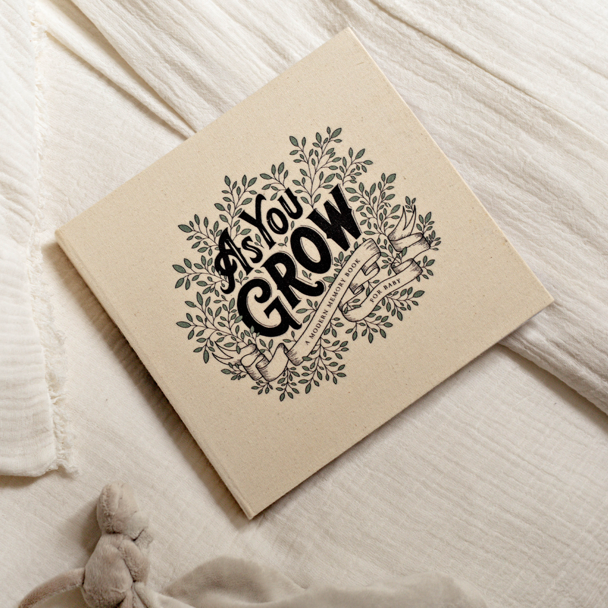 Notebook with 'As You Grow' design on a soft fabric background