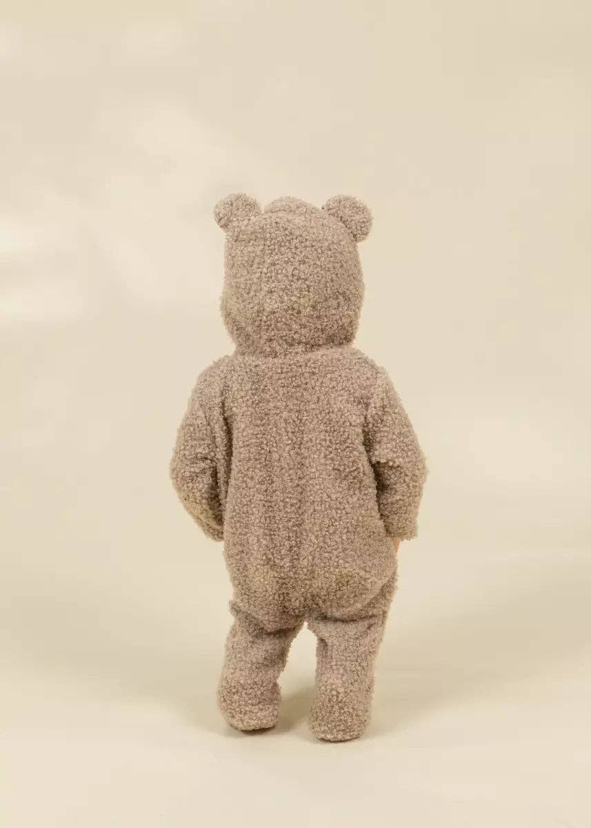 A teddy bear hooded one-piece outfit in a textured, bouclé-like taupe fabric, shown from the back on a neutral cream background.