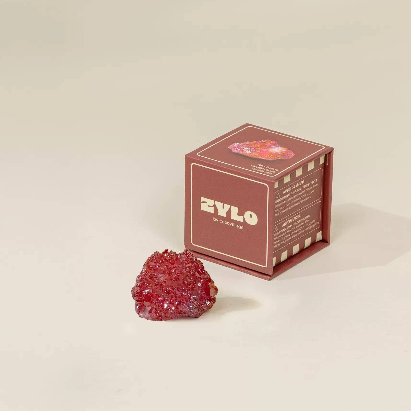 Red crystal-like object next to a ZYLO branded box on a beige background