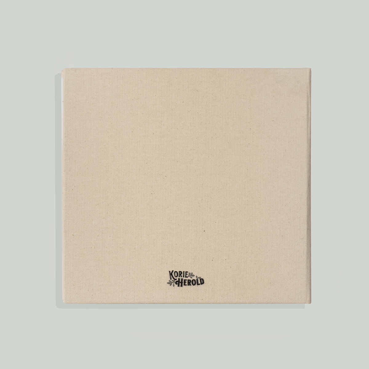 Beige book with a brand logo on a light gray background