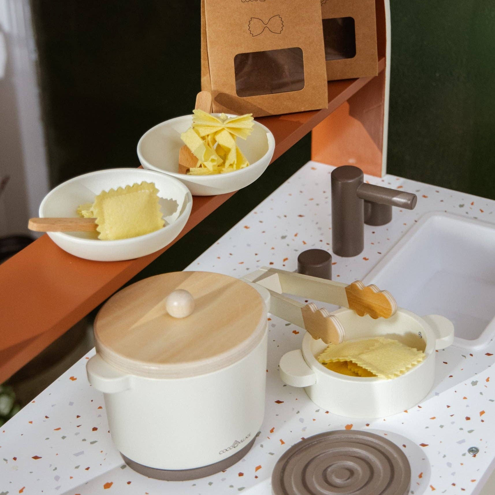 Kitchen setup with a pot, bowls, and kitchen tools on a speckled countertop.