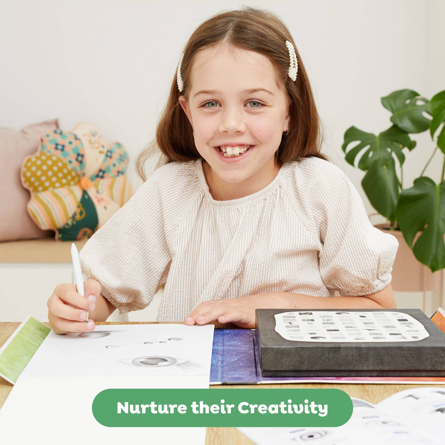 Young girl sitting at a table with art supplies, smiling, with a text overlay 'Nurture their Creativity'.