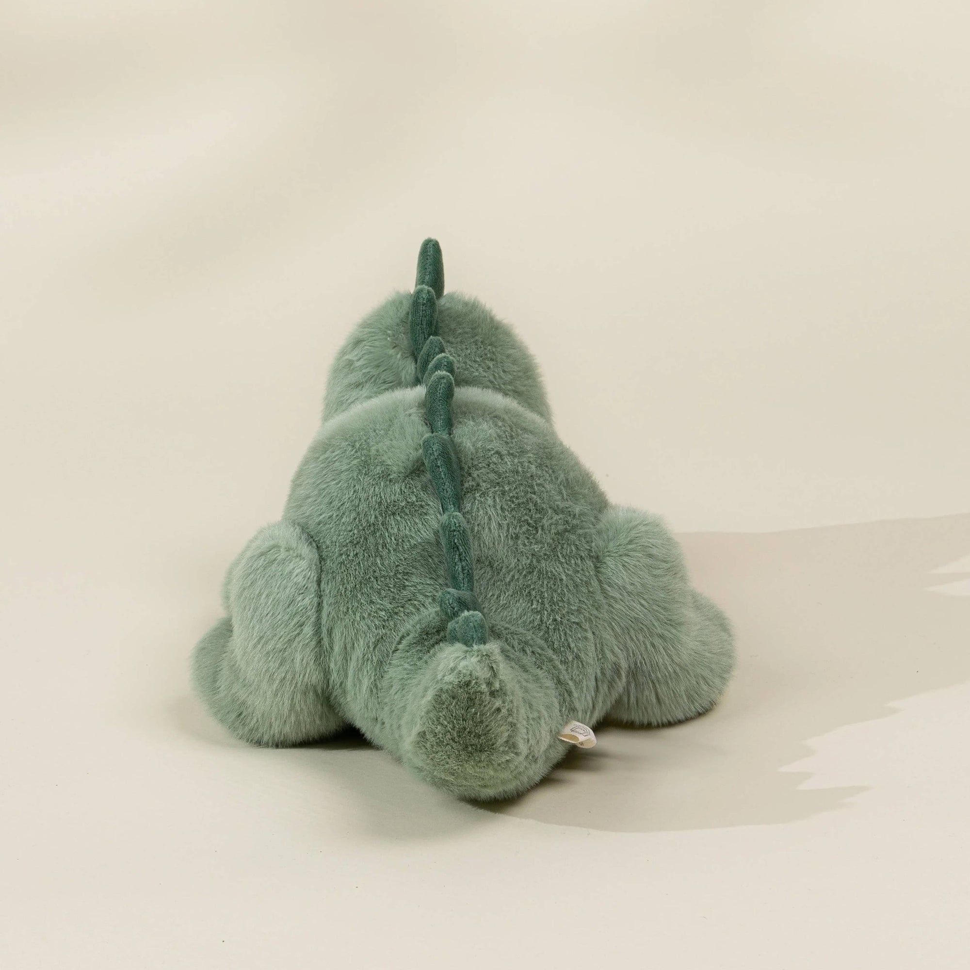 Green plush toy on a white surface with a plain background