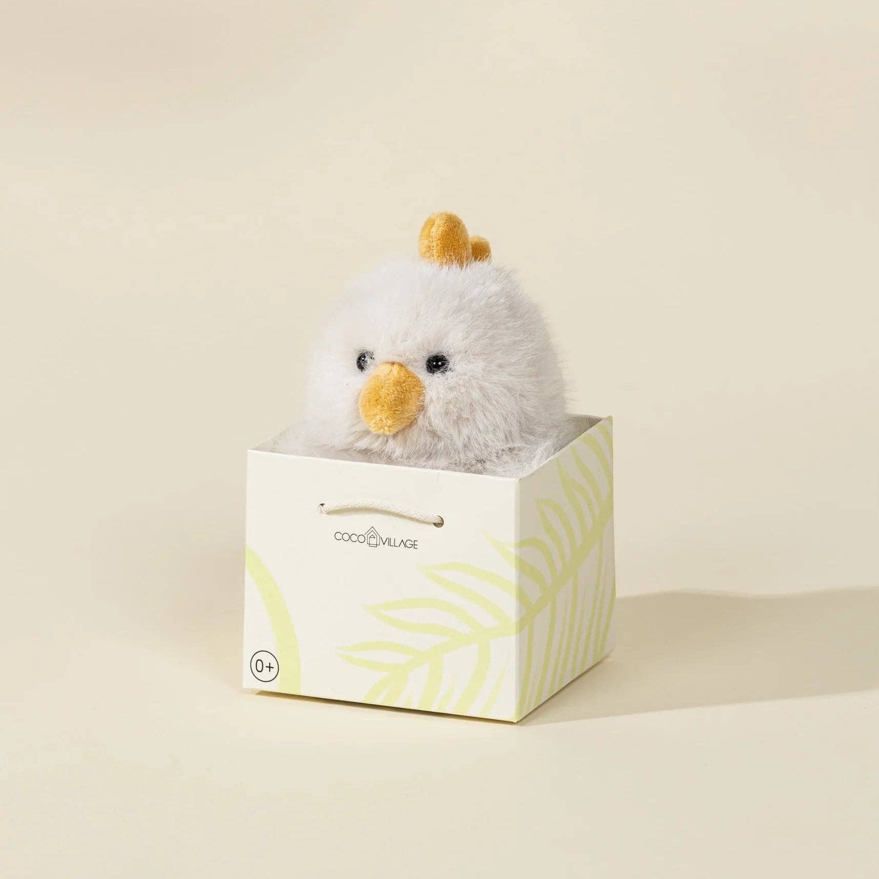 Small plush chick toy in a box with a light background