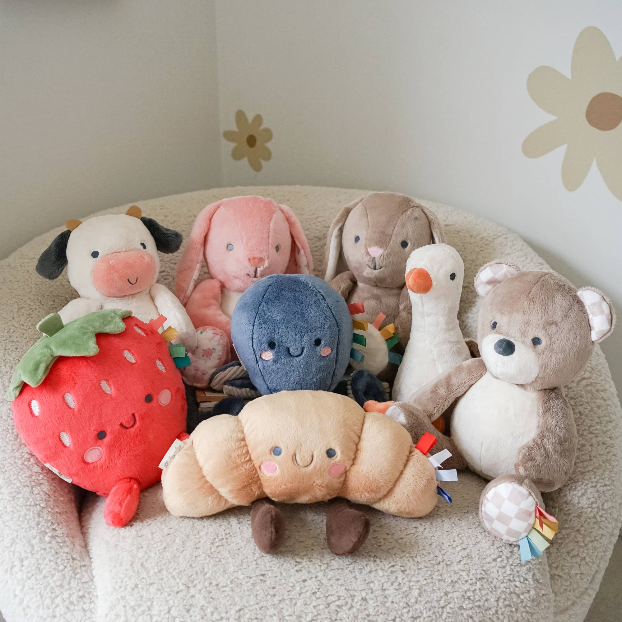 Collection of soft toys on a cushion with floral wall decorations