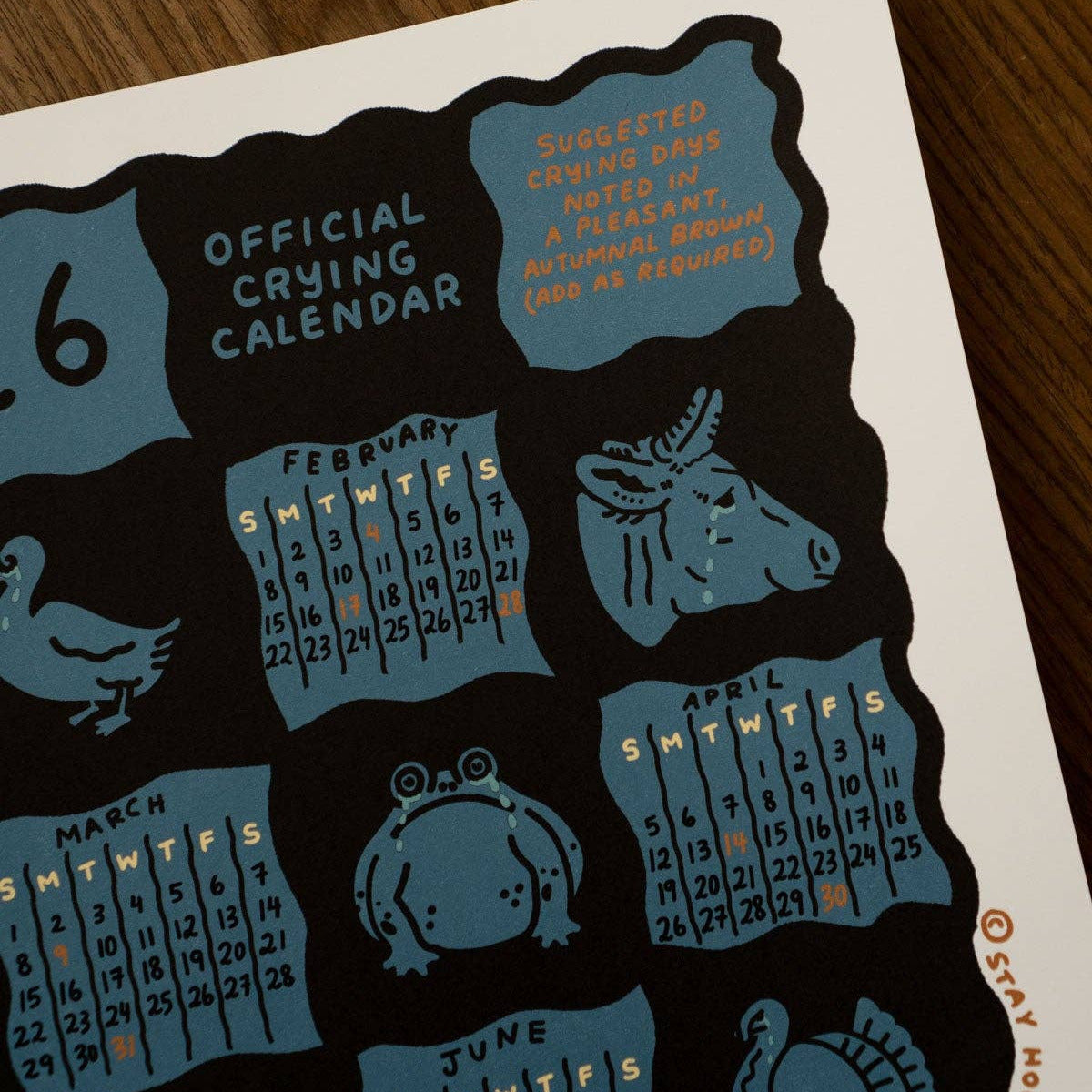 Calendar with illustrations of crying faces and months on a wooden surface