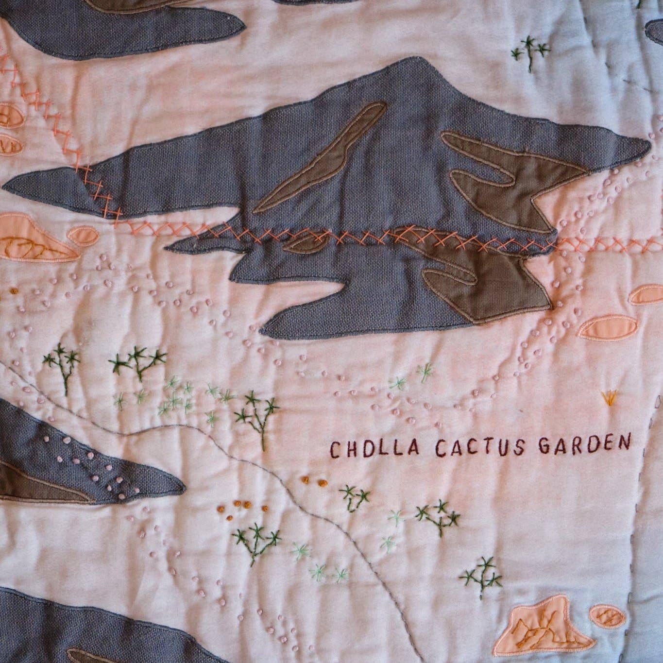 Quilt with embroidered cholla cactus design on a beige background
