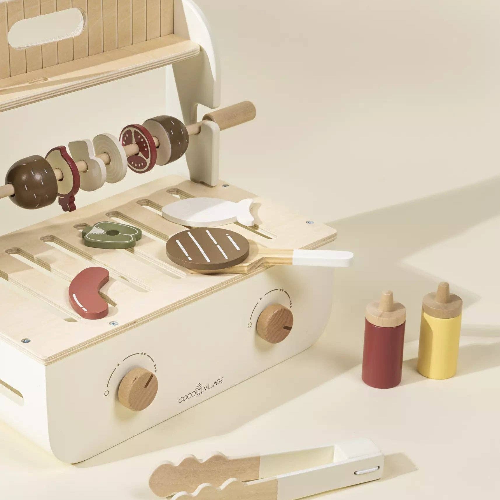 Wooden toy kitchen set with various utensils on a light background