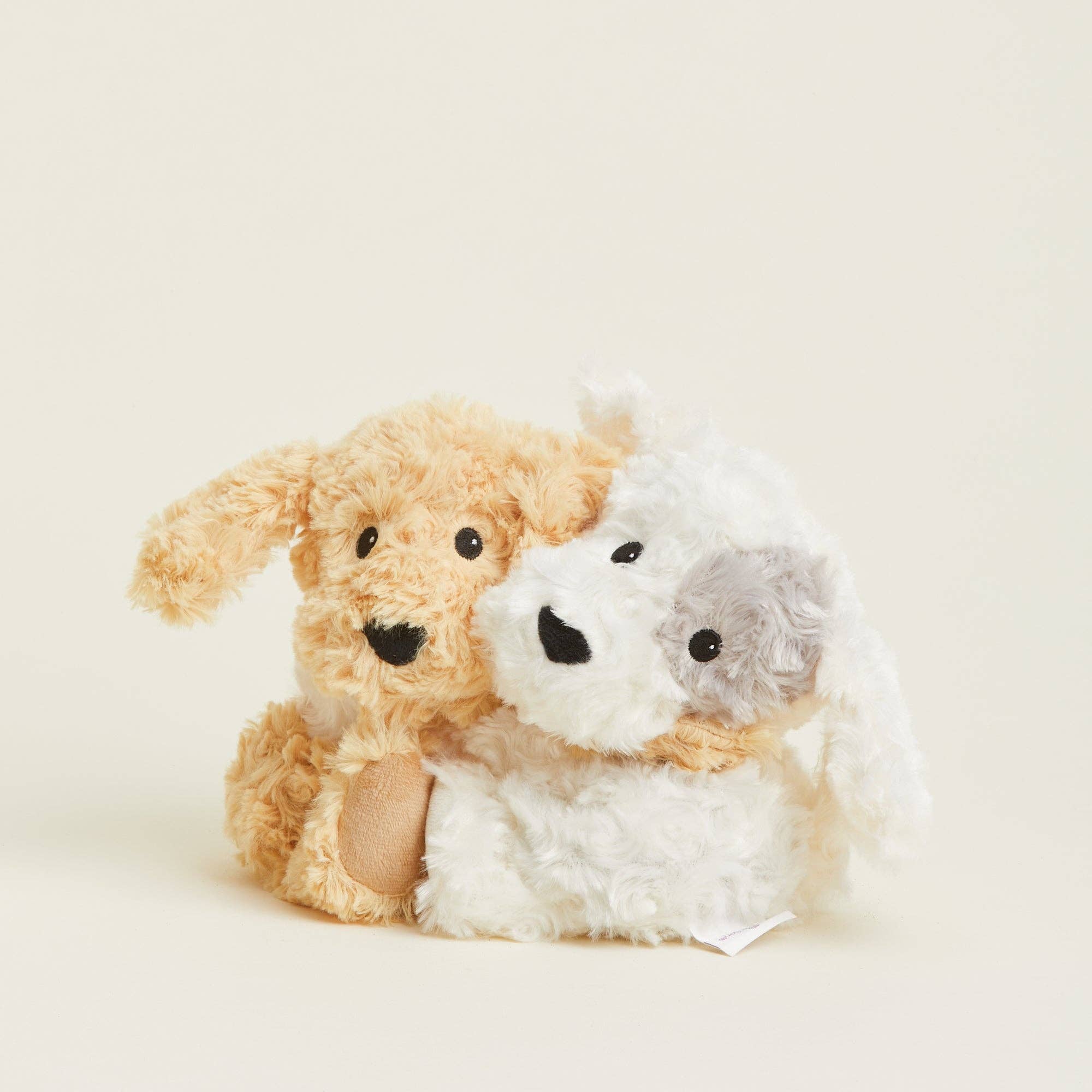 Two plush toys, one brown and one white, on a light beige background