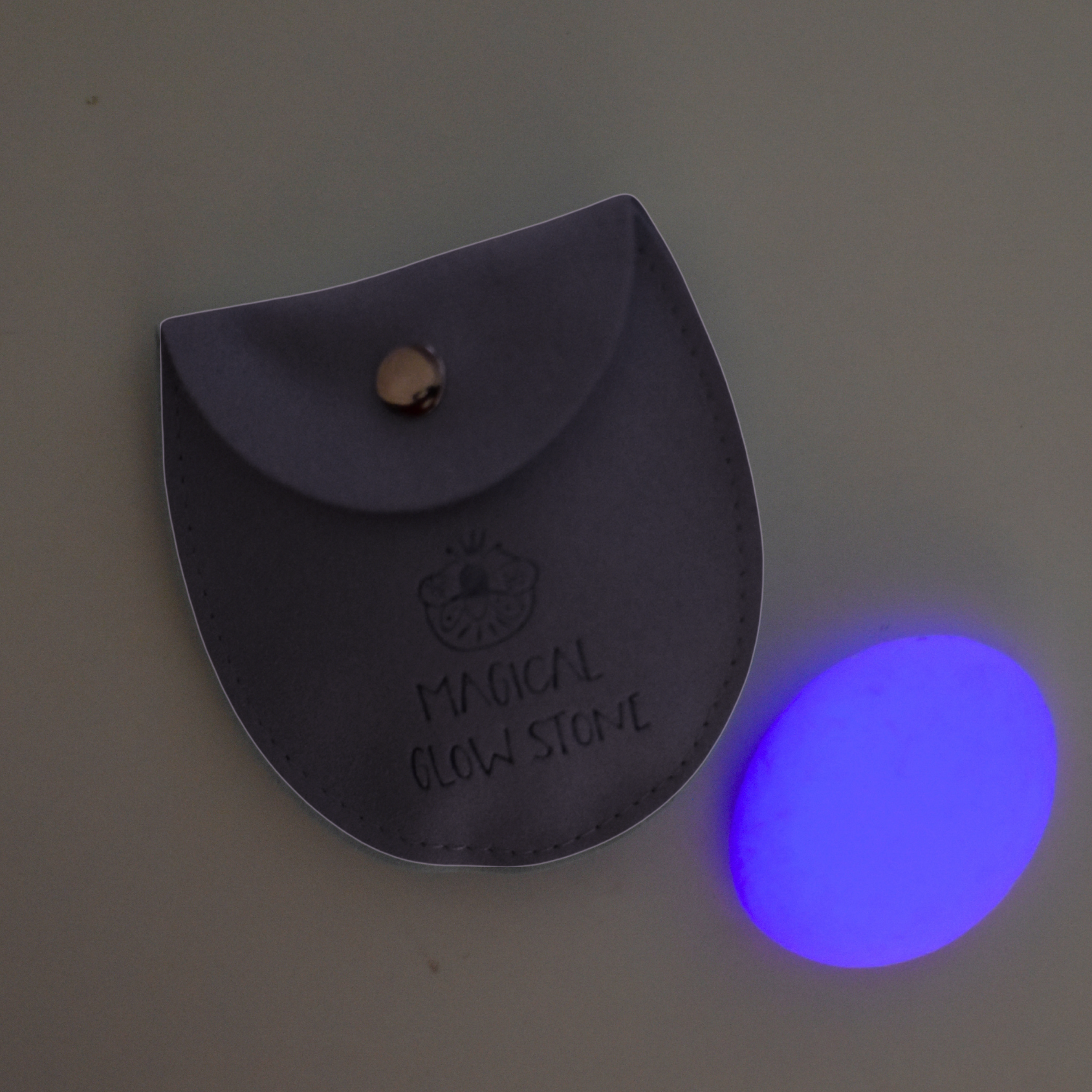 Black leather pouch with 'Magical Glow Sign' text next to a glowing blue orb on a gray background