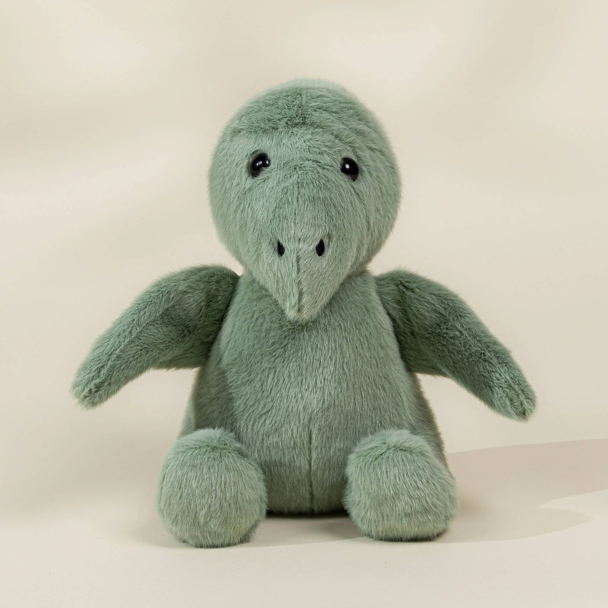 Green stuffed toy dinosaur on a beige background