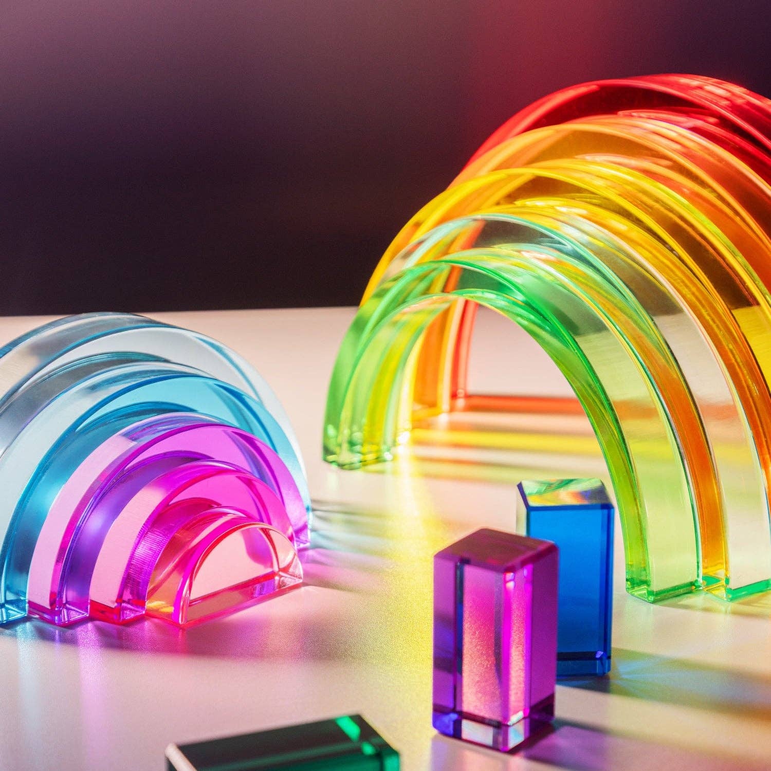 Colorful transparent arches and rectangular blocks on a reflective surface with a dark background