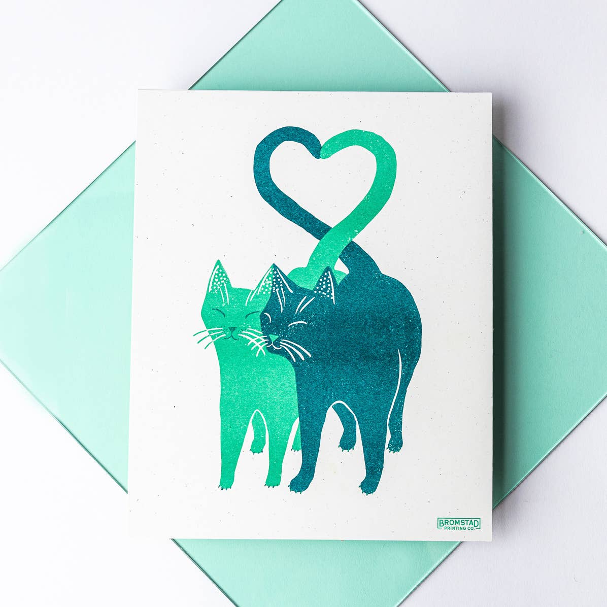 Card with two cats forming a heart shape on a light green envelope