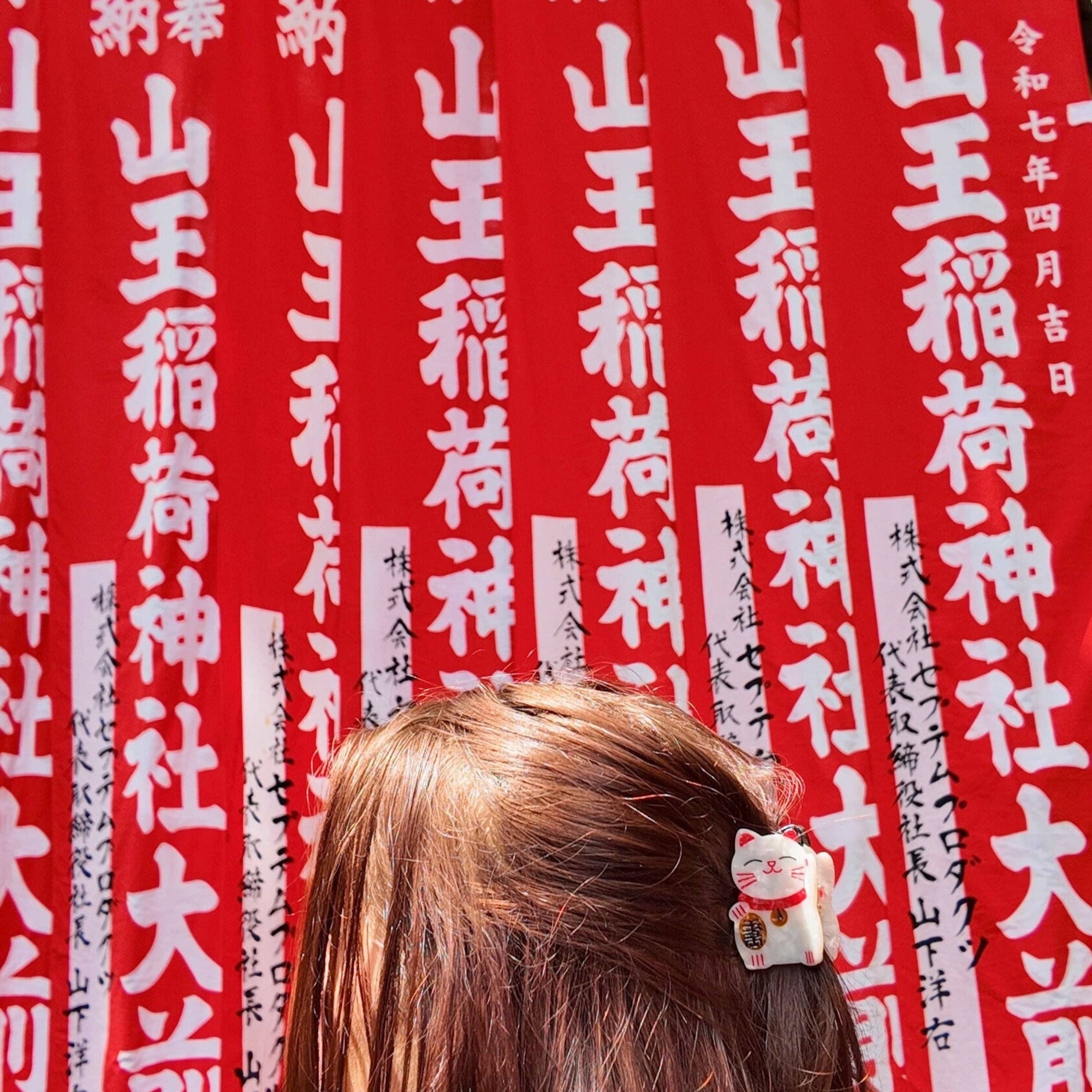 Person with a hair clip featuring a small dog figurine in front of red banners with white text.
