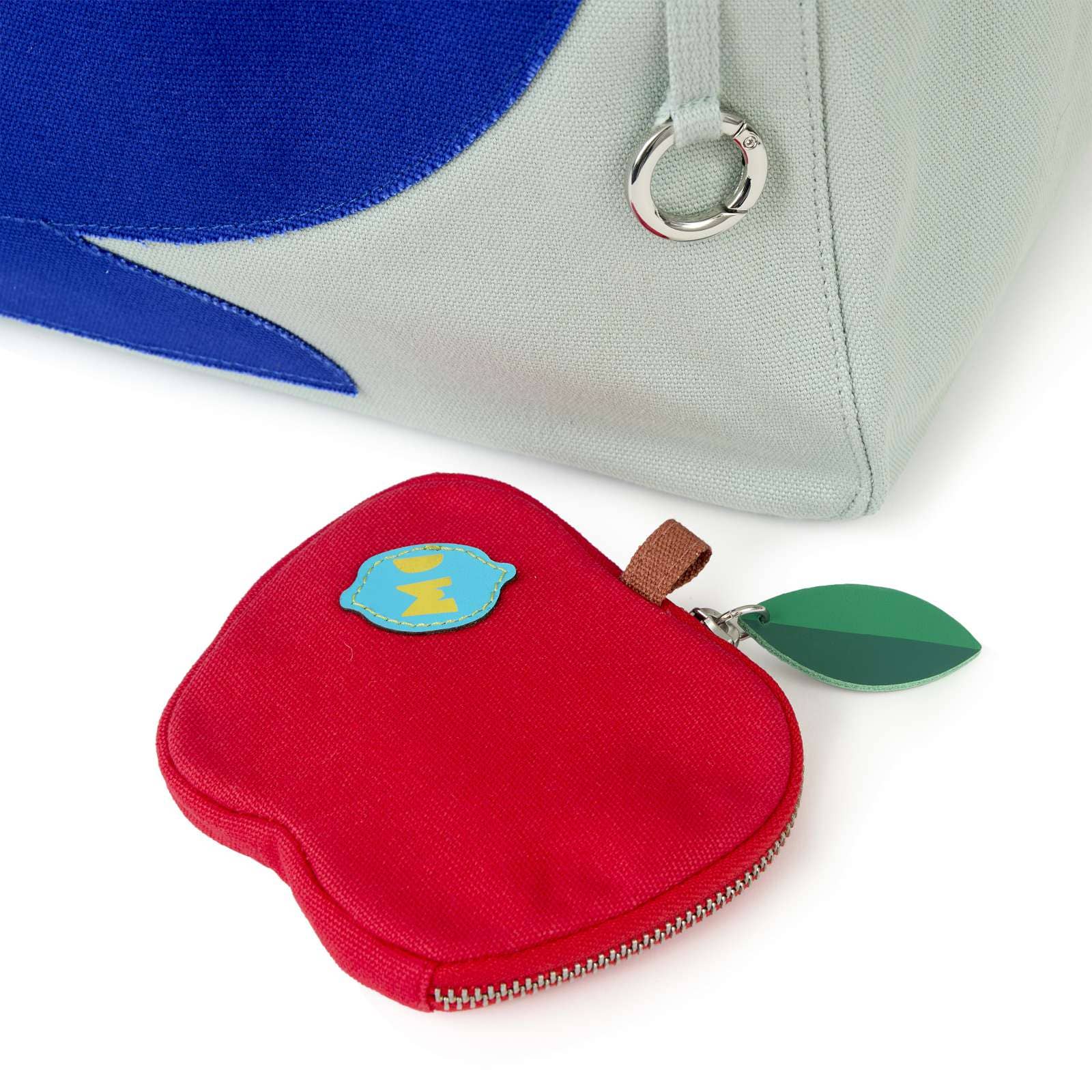 Red apple-shaped coin purse with a blue label and green leaf on a white background