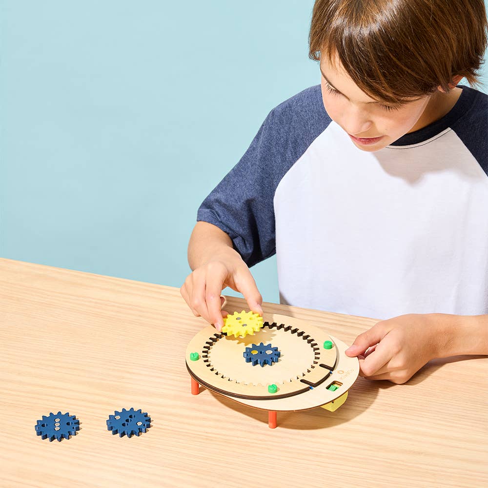 Child playing with a wooden gear toy on a table