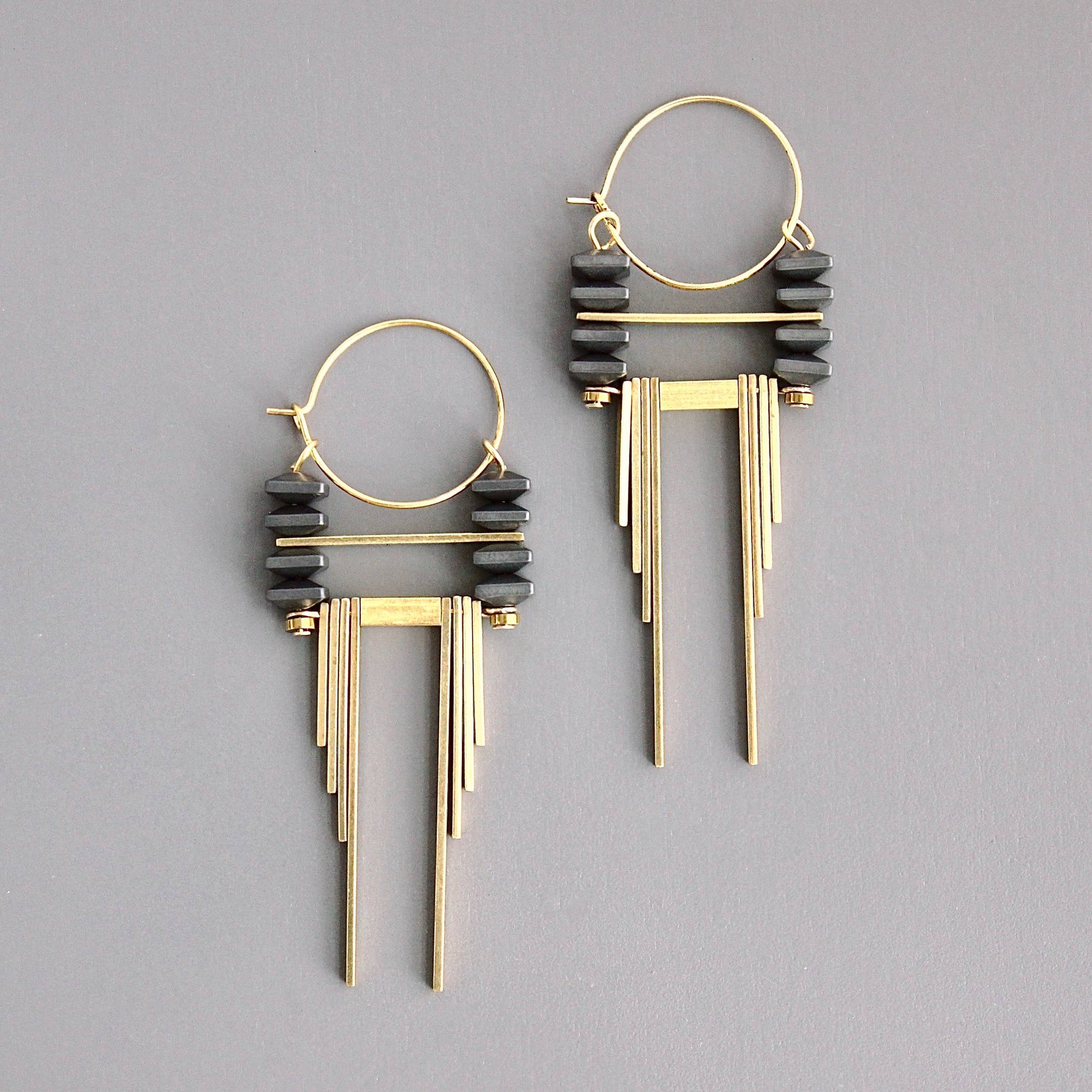 Gold and black earrings on a gray background