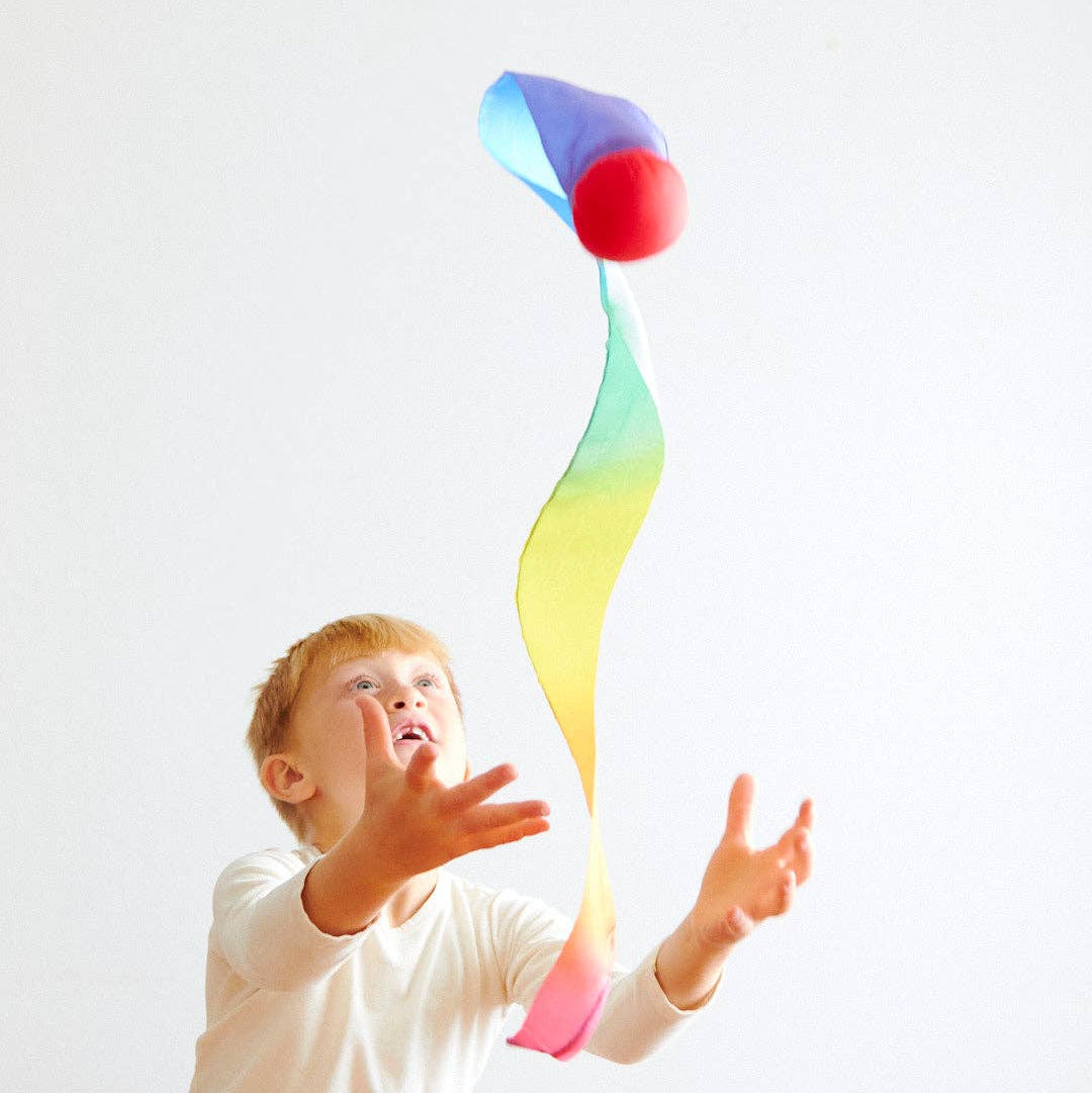 Child playing with a colorful ball on a white background