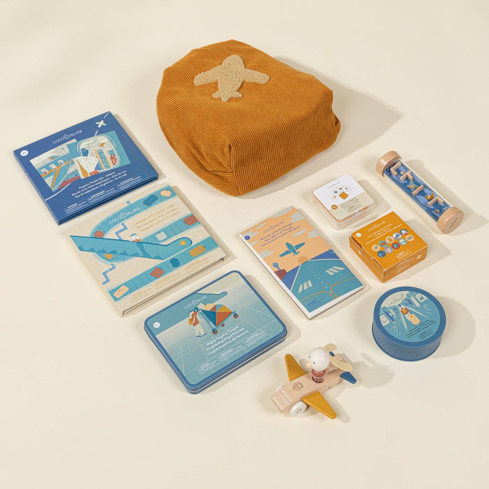 Collection of travel-themed items including a brown bag, cards, a toy airplane, and small containers on a beige background.