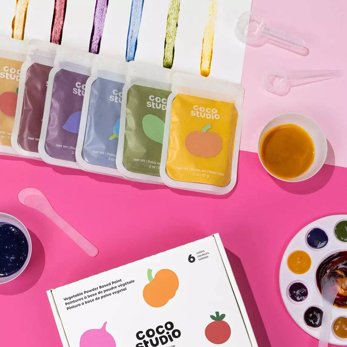 Coco Studio product packaging with colorful containers on a pink background
