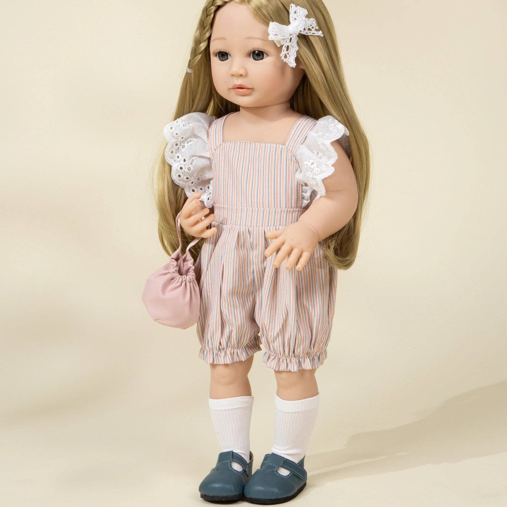 Doll wearing a pink striped romper with ruffled sleeves against a beige background