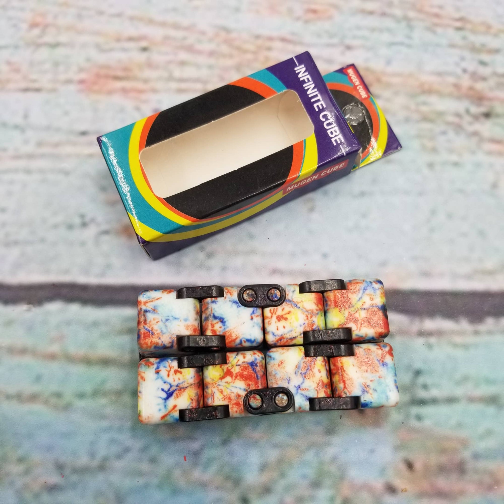 Colorful phone case with 'Infinite Cube' packaging on a textured surface