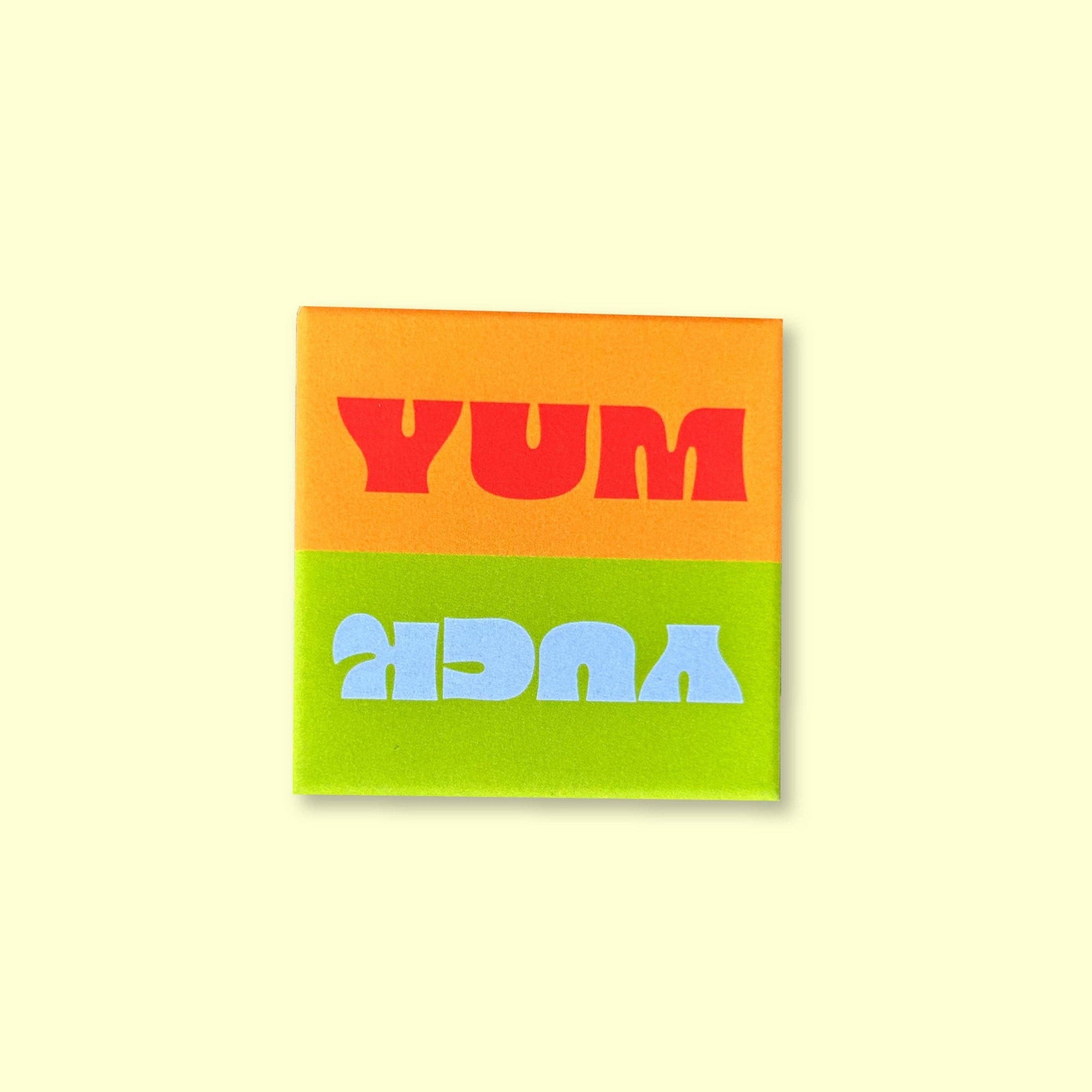 Notebook with 'YUM' on an orange page and 'KEDRA' on a green page against a light yellow background