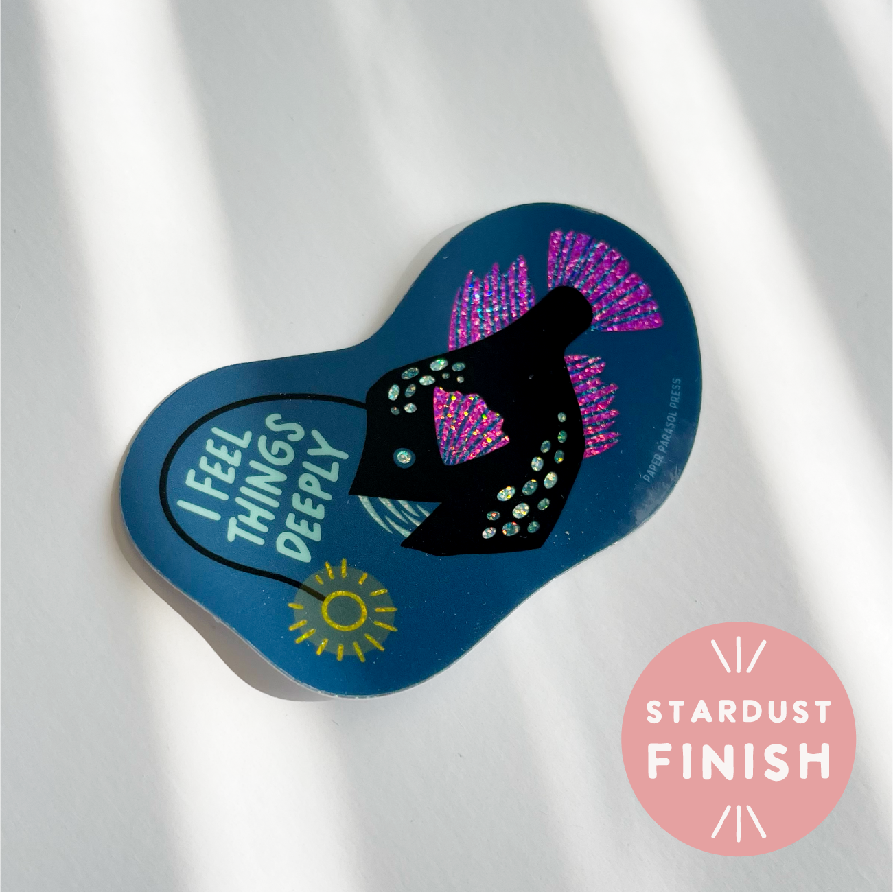 Blue sandal-shaped sticker with 'I Feel Things Deeply' text and stardust finish on a white background