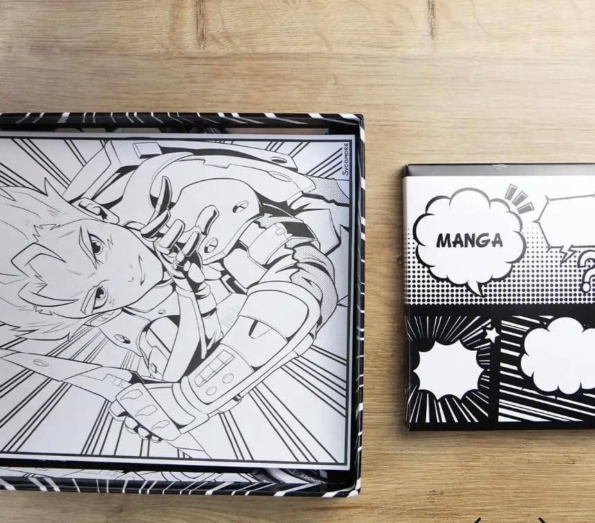A black and white manga-themed box with comic book panel illustrations sits on a light wood surface next to a smaller matching box featuring a speech bubble with the word 'MANGA'.