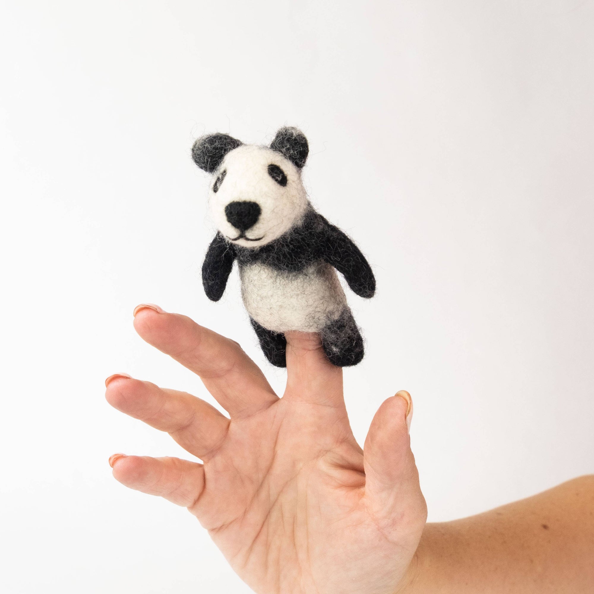 Panda finger puppet on a person's finger against a white background