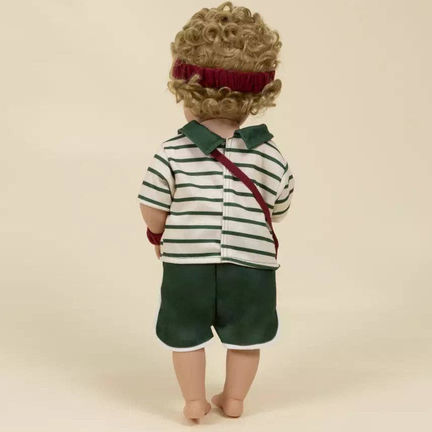 Doll wearing a striped shirt and green shorts on a beige background