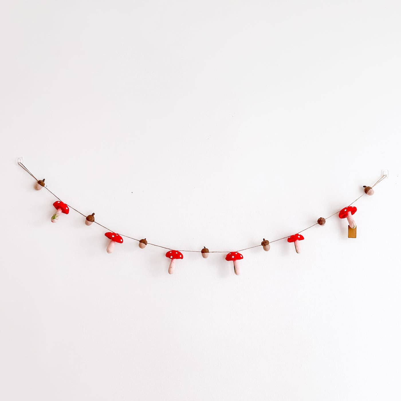 Decorative string with red mushroom-shaped ornaments on a white background