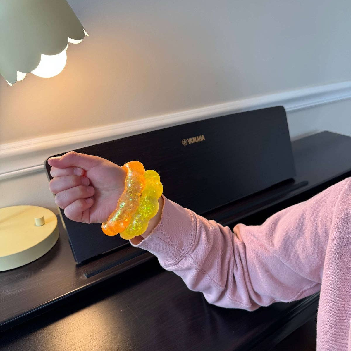 Person wearing a colorful bracelet on a piano