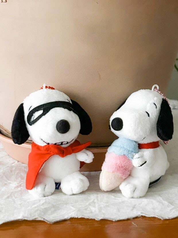 Two plush toys resembling a dog with black ears and a red bow tie on a light surface.
